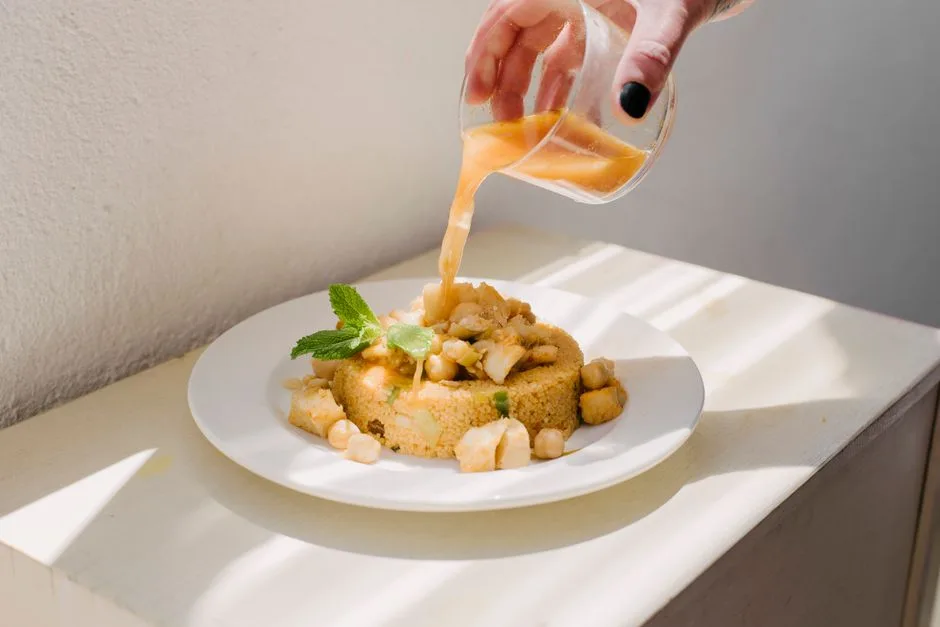 Bouillon versé sur un dôme de semoule de couscous garni de pois chiches